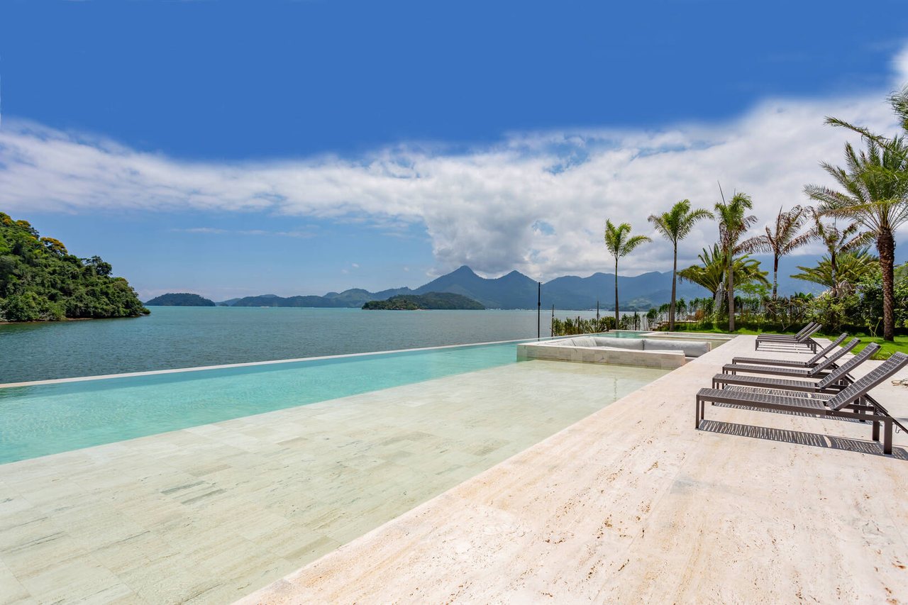 A piscina de borda infinita em travertino parece desaguar diretamente no oceano, entre as ilhas da Baía de Angra